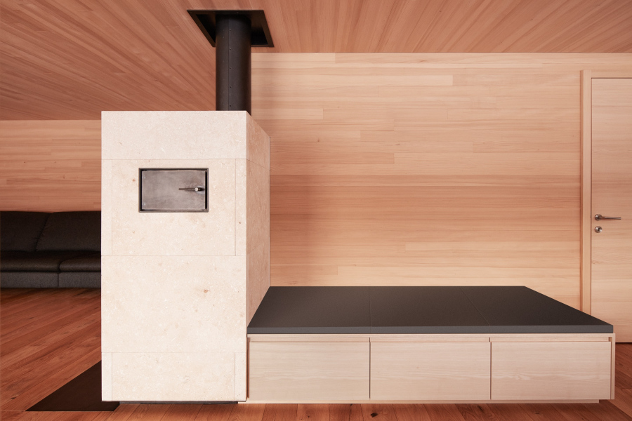 Ofenbau Voppichler – Grundofen verkleidet mit Schwarzstahl und Kalkstein, inklusive Ofenbank.